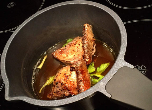 Stielkasserolle Edition 9 mit Bräunung von Fleischstücken und Sellerie in der Pfanne, Aluminium-Druckguss, Antihaftbeschichtung, auf Herd.