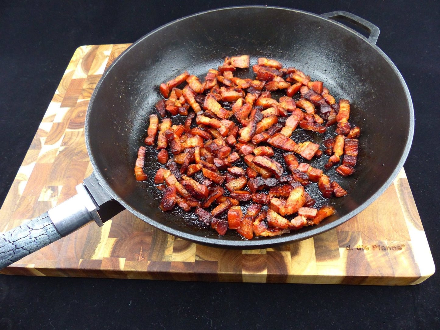 Gusseisenpfanne PUREiron mit gebratenem Speck auf Holzbrett, abnehmbarer FlameWood-Stiel.