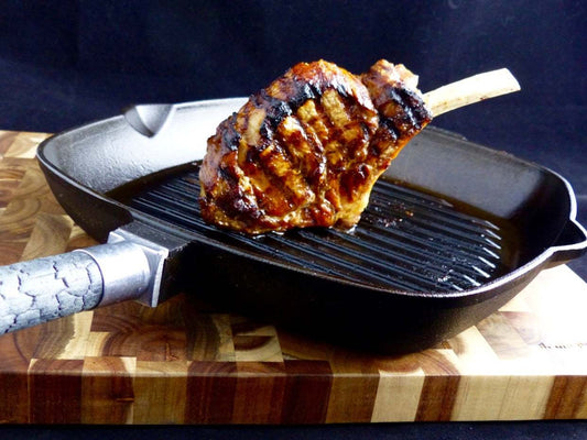 PUREiron - die Grillpfanne aus purem Gusseisen: Grillpfanne aus Gusseisen mit abnehmbarem FlameWood-Stiel, Steak auf Grillrost, PUREiron.