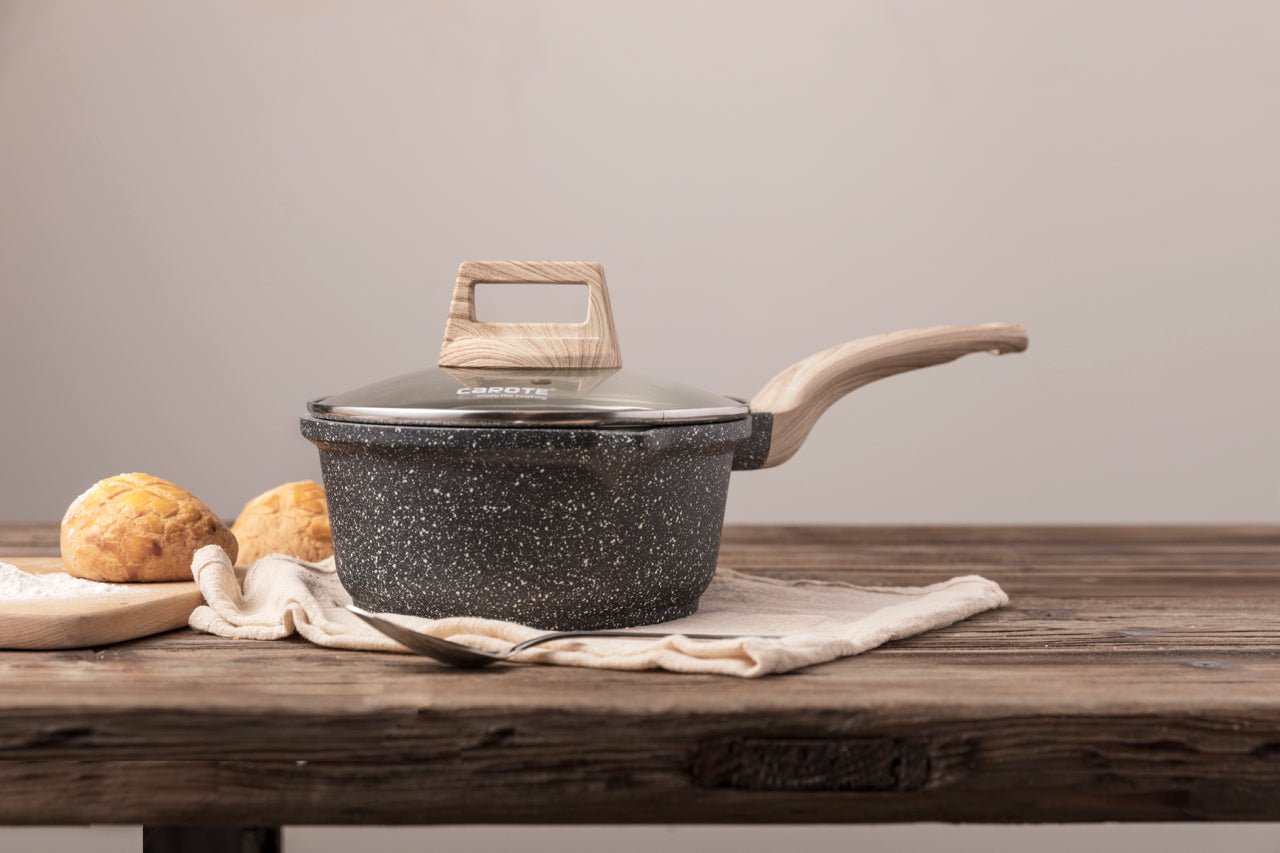 Stielkasserolle aus Aluguss mit Glasdeckel und Holzeffekt-Griff auf Holztisch.