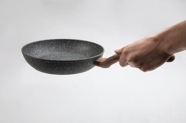 Kleine Pfanne der Serie Air (Durchmesser 20 cm) in linker Hand vor weißem Hintergrund.