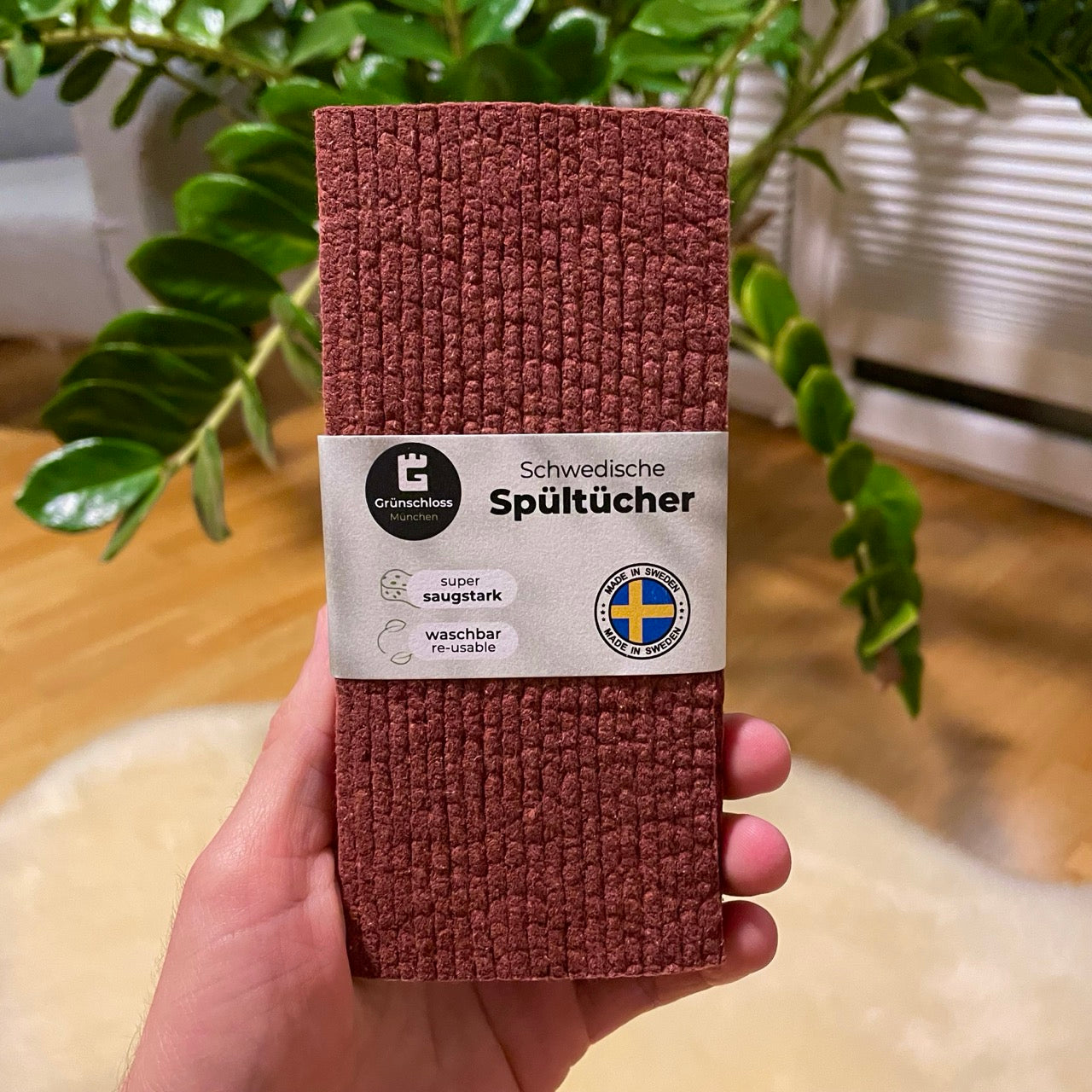 Hand hält schwedischen Spüllappen in Rotwein-Farbe mit Label, saugstark und waschbar, nachhaltiges Küchentuch aus Schweden