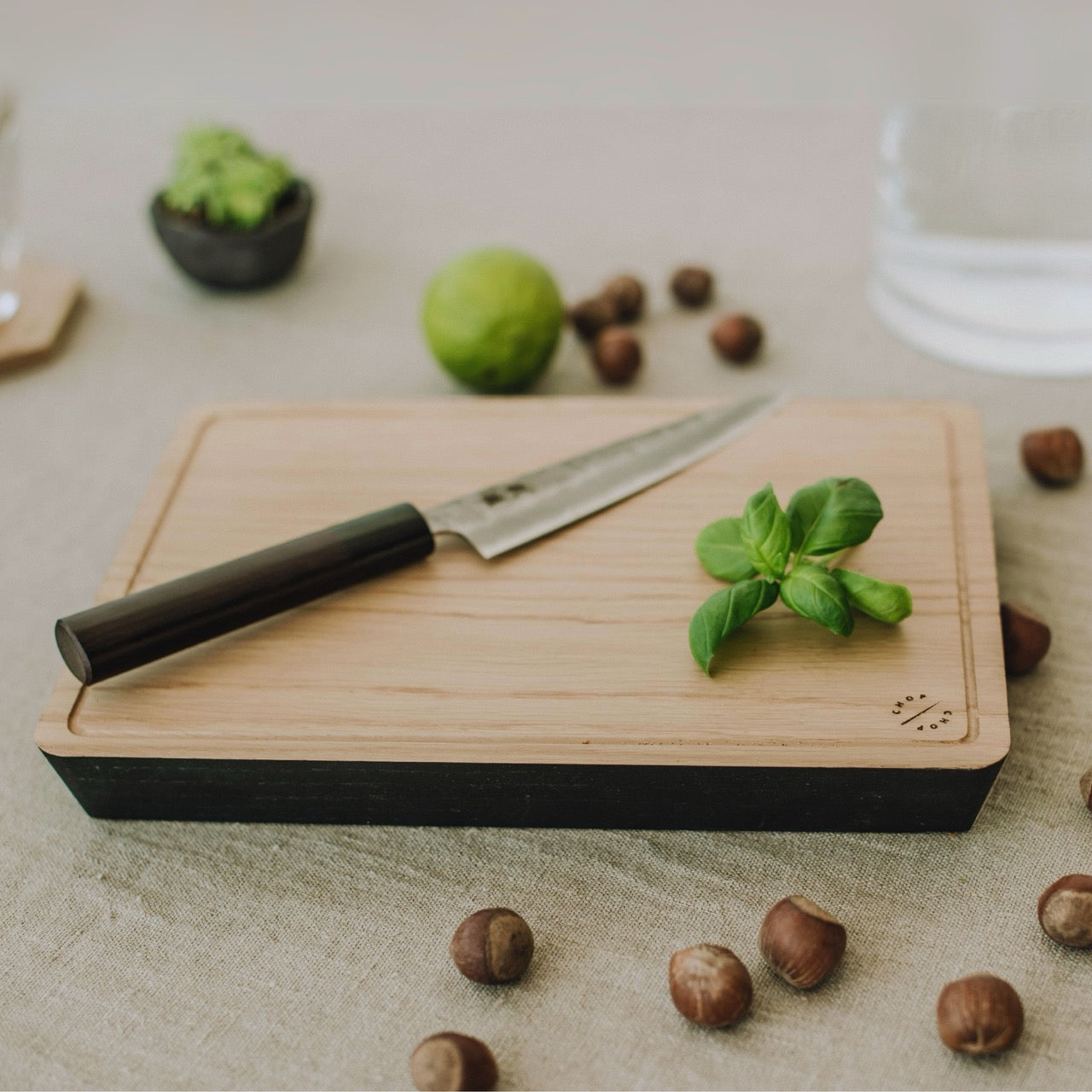 Steak Schneidebrett aus massiver Eiche mit Saftrinne und schwarzem Rand, Messer und Kräuter darauf