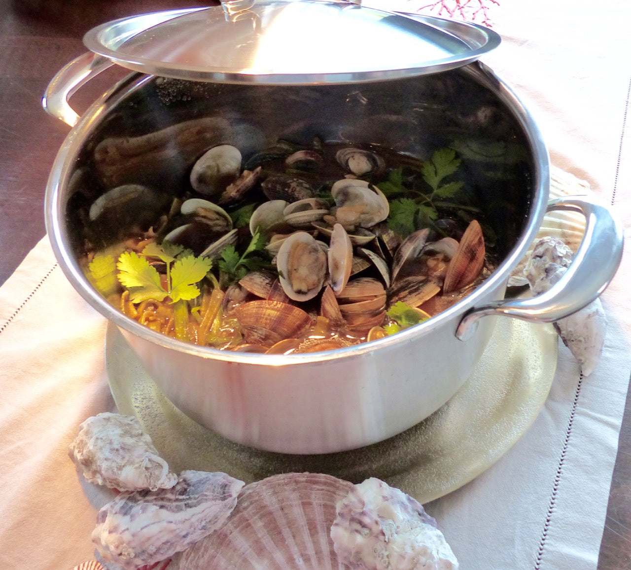 Edelstahl-Kochtopf Edition 10 mit Muscheln und Kräutern gefüllt, zeigt hochwertigen seidenmattierten Topfkorpus und Aufliegedeckel.