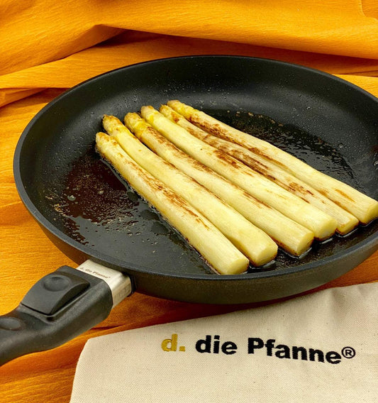 Flache Aluguss-Pfanne der Edition 13 mit abnehmbarem Stiel, gebratener Spargel, orange Hintergrund.