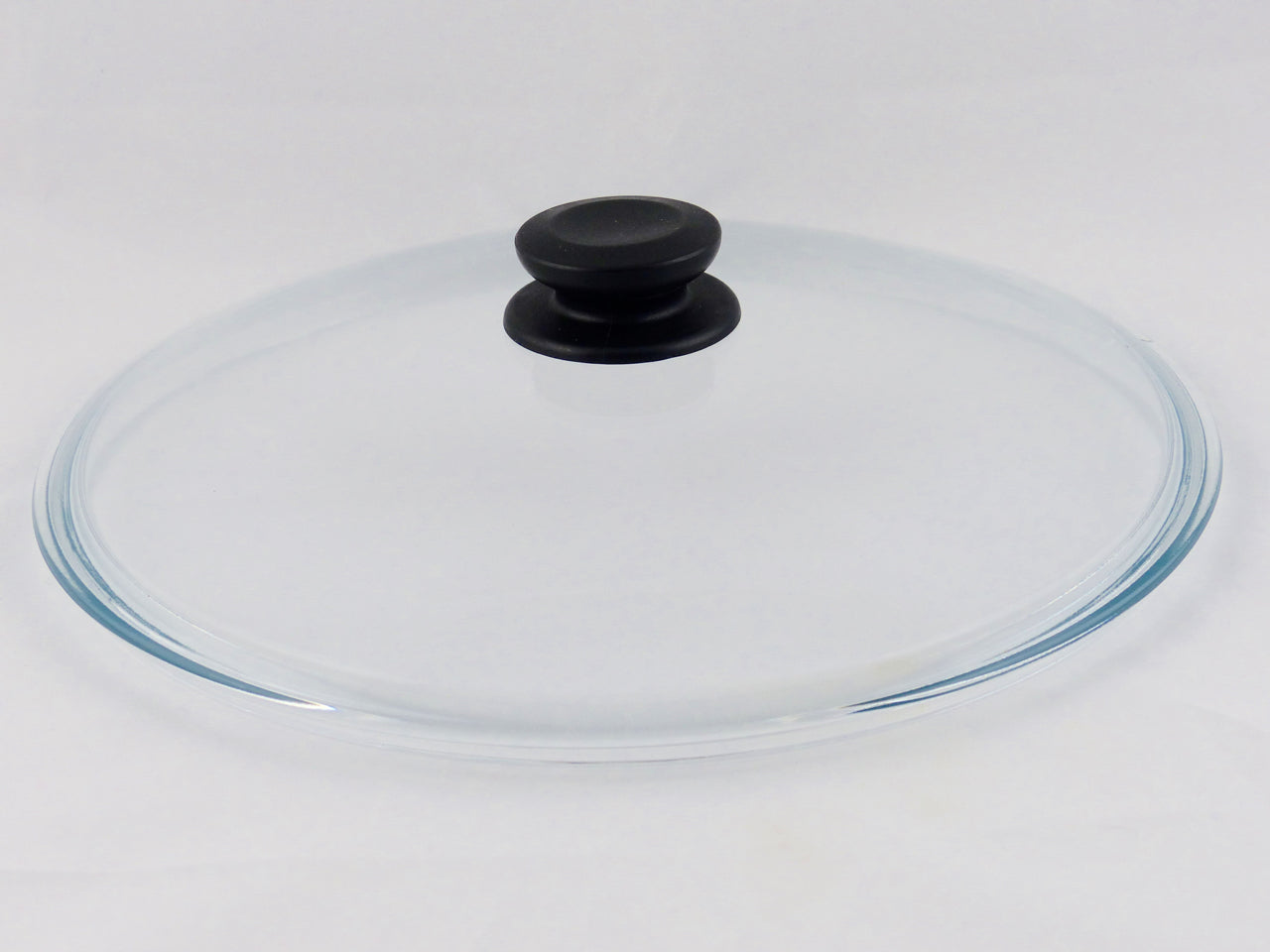 Zu sehen ist ein Pressglasdeckel aus Borosilikatglas. Er trägt einen schwarzen Knopf aus Bakelit.