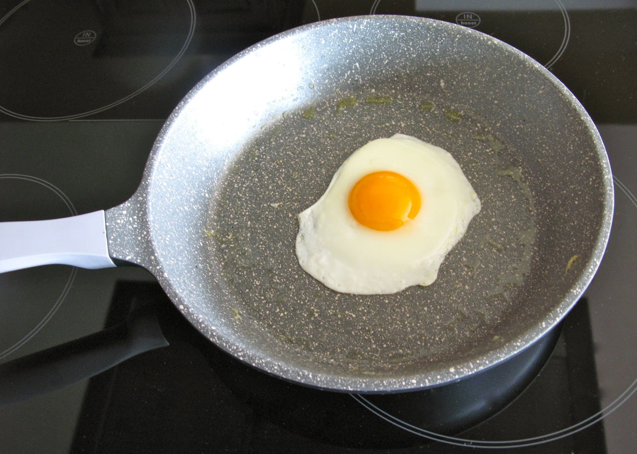 Universalpfanne aus Aluguss Edition 1 mit Spiegelei auf Herd. Die Pfanne hat einen Durchmsser von 24 cm, ist induktionsgeeignet und premium-antihaftbeschichtet.